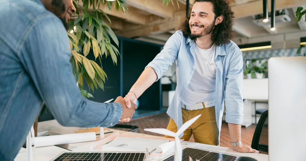 Two men shaking hands at desk
